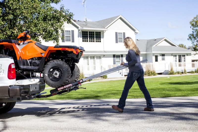 Woman locking pivoting ramps into place to transport ATV - MAD-RAMPS