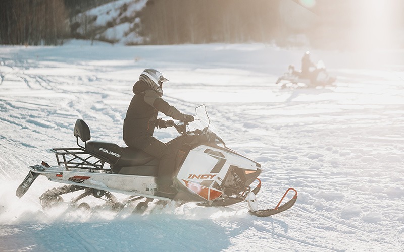 two people riding snowmobiles
